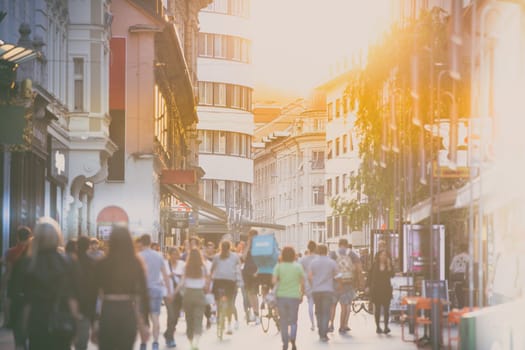 Blurred crowd of people on Copova pedestrian street in Ljubljana at sunset. Urban lifestyle and mobility concept