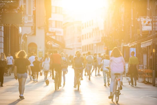 Blurred crowd of people on Copova pedestrian street in Ljubljana at sunset. Urban lifestyle and mobility concept