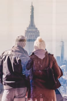 Romantic couple enjoying in New York City panoramic view. Manhattan downtown skyline with illuminated Empire State Building and skyscrapers seen from observation deck terrace.