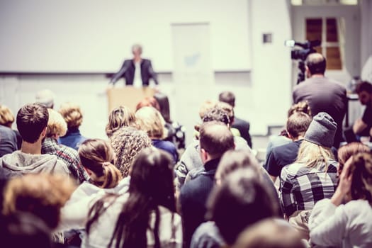 Speaker giving a talk in conference hall at business event. Audience at the conference hall. Business and Entrepreneurship concept. Focus on unrecognizable people in audience.
