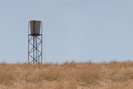 Water tank in the middle of dry pastures. Lack of water resources for cattle concept