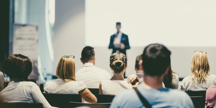 Male speaker giving a talk in conference hall at business event. Audience at the conference hall. Business and Entrepreneurship concept. Focus on unrecognizable people in audience.