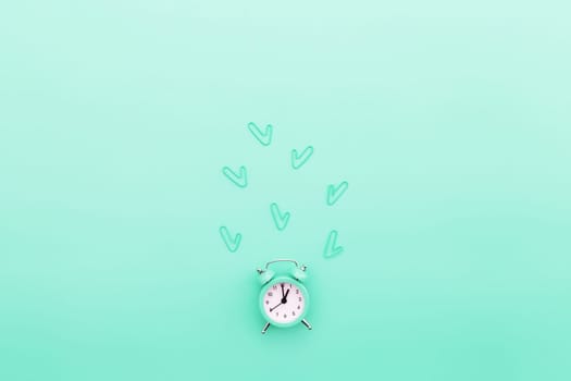 Back to school, office work conceptual flat lay with alarm clock, clips and copy space area for text. Concept of time to work, be in time and wake up early idea. Turquoise background and alarmclock