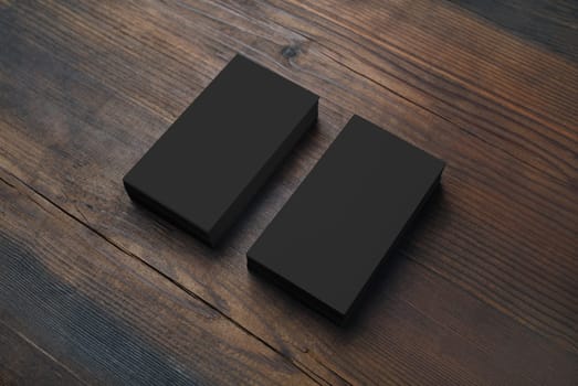 Photo of blank black business cards on wooden background. Template for branding identity.