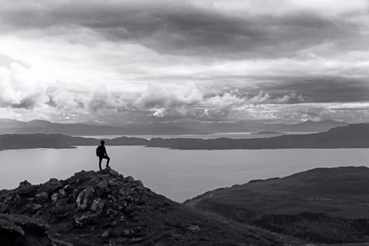 A climber stands on a peak high above a large lake