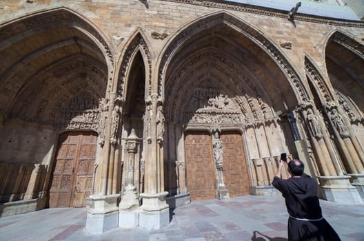 Leon, Spain - June 25th, 2019: Friar taking picture to Leon Cathedral, Spain. Main Entrance