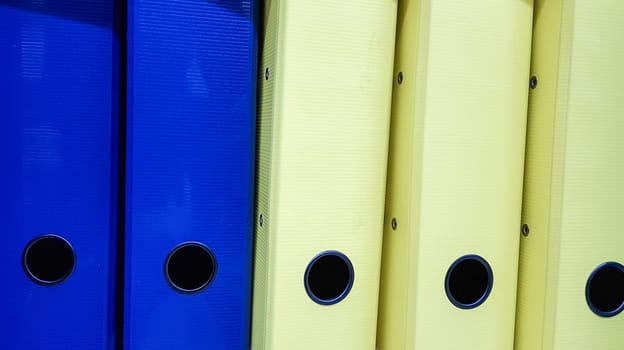Various office folders on a supermarket shelf. Plastic and paper folders with documents are on the shelf of the cabinet