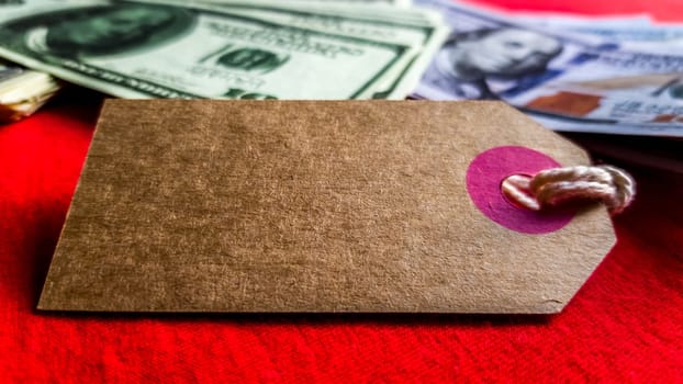 Empty cardboard tag for the inscription Black Friday with American dollars on a red background. Background, holiday concept. Black Friday - International Day of Shopping, Promotions, Discounts, Sales. Sales season is the fourth Thursday of November. Copy space, place for text.