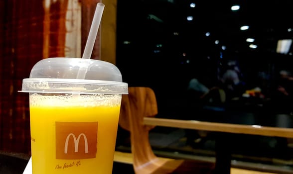 Ukraine, Kiev - August 25, 2019: a glass of McDonalds orange juice on a table in a fast food restaurant with blurred background interior.
