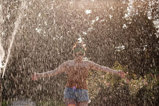 happy girl runs through a fountain in a green park in the sunshine.