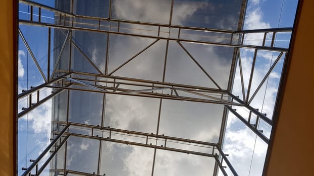 Structural glazing of the facade. Abstract background with glass ceiling elements in a modern building. view of the blue sky through a glass window, separated by lattice elements