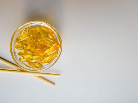 Fish oil capsules on a saucer with chopsticks. Bunch of vitamin omega 3 pills on a white background. Close-up, top view, high resolution product. Metabolism in the body. Body calcium