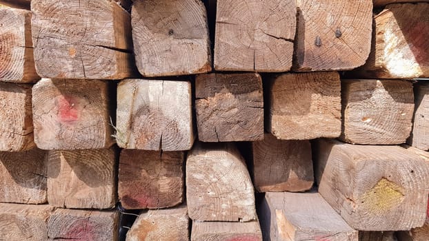 Stacked lumber. Folded wood.Closeup wooden boards.The surface of the end of the board.Lots of planks stacked on top of each other in the warehouse.Lumber for use in construction
