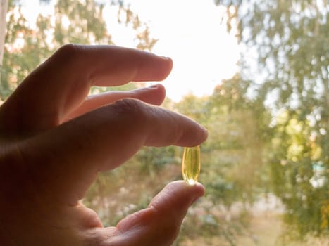 Vitamin D is healthy when there is no sun. Yellow soft shell vitamin capsule against the blue sky on a sunny day. Treatment concept. Vitamin And Supplement. Diet food and healthy lifestyle concept