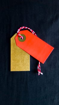 Two colored tags on a white rope, black background. Vertical photography. Copy space, place for text, flat lay. vertical position of the photo.
