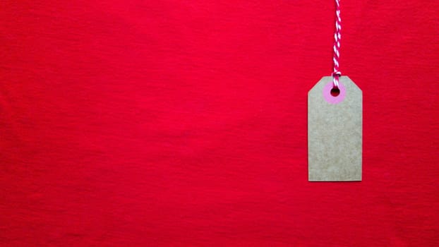 Red tag tag hanging on a red rope on a red background. Copy space, place for text, flat lay