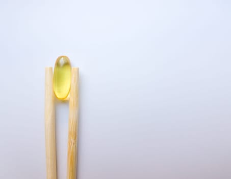 Fish oil capsules with Chinese chopsticks. Omega 3 on a white background. High Resolution Product. Food supplement. Vitamins for a healthy lifestyle. Fatty acid. Metabolism in the body