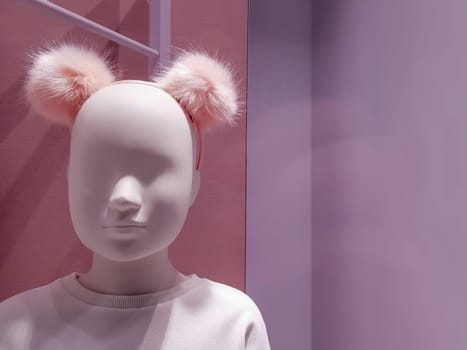 Portrait of a white mannequin girl on a background of bright colorful warm pink shades. Little doll in a shop window. Boutique with a young mannequin. Department of children's clothing. Face close up.