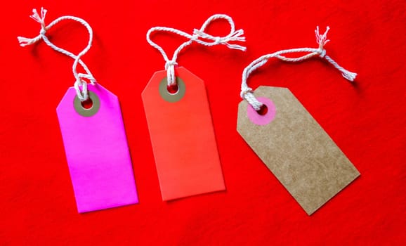 three colored tags on a white rope, red background.