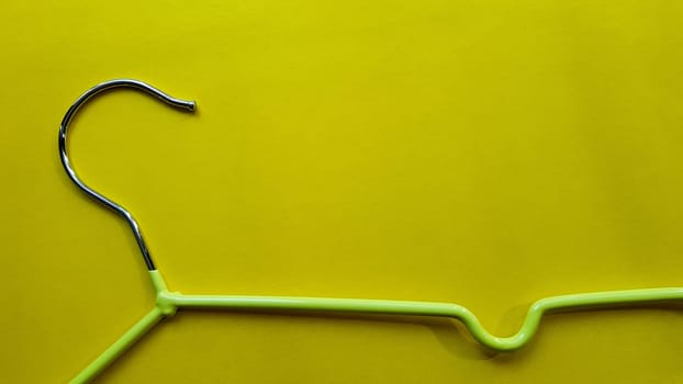 Hanger for clothes on a yellow background. Green hanger. Background with copy space. Black friday, shopping day.