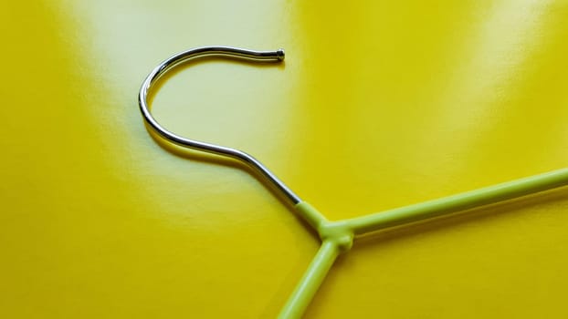 Hanger for clothes on a yellow background. Green hanger. Background with copy space. Black friday, shopping day.