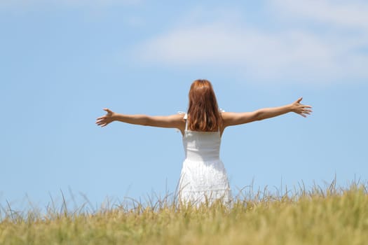 Happy woman celebrating outstretching arms in a field