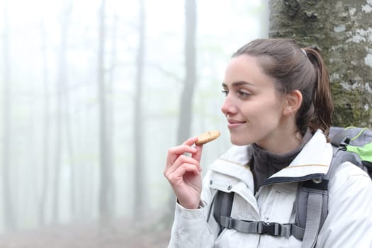 Trekker resting eating cookie in a forest
