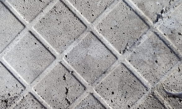 Background of an old darkened shabby and scratched gray concrete floor with traces of floor tiles. Concrete texture, trace of fallen off tiles of dark gray color, mesh structure, concrete pieces.