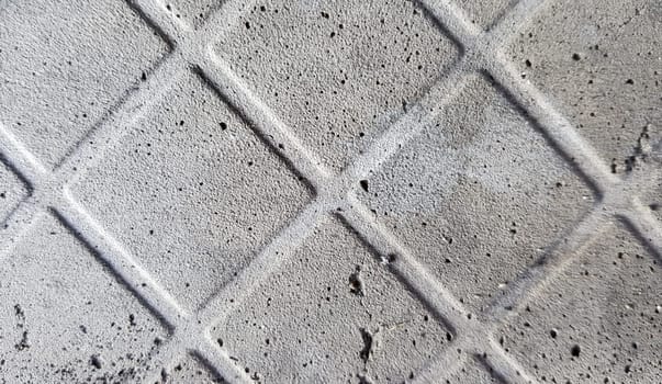 Background of an old darkened shabby and scratched gray concrete floor with traces of floor tiles. Concrete texture, trace of fallen off tiles of dark gray color, mesh structure, concrete pieces.