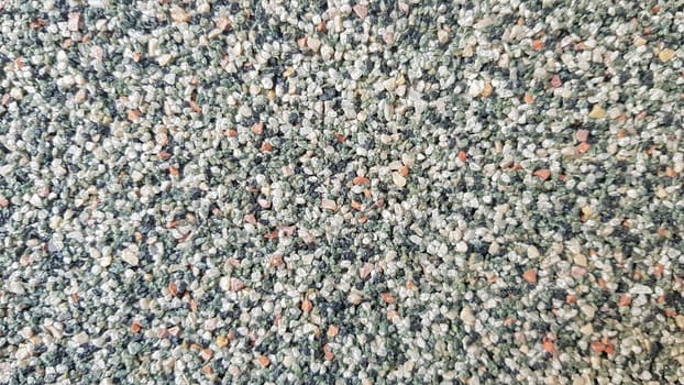 Gray concrete surface with multi-colored marble chips. Foreground. Dark gray marble chips. Wall, facade trimmed with marble chips.