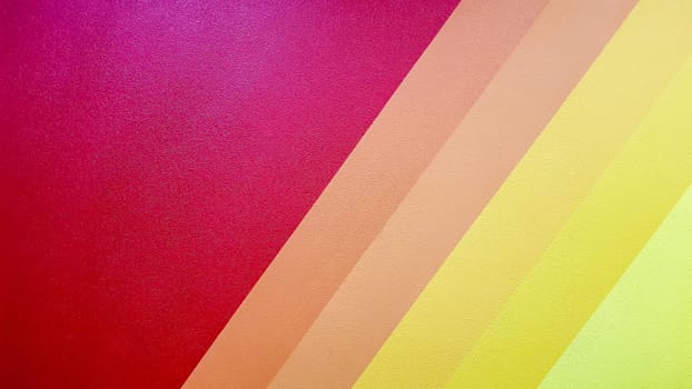 The wall is painted in red, pink, orange, yellow color with diagonal lines. Colorful background for your text and message with copy space