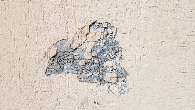 dent on a yellow concrete wall. Hole in the wall with foam insulation. Crack on the yellow wall with decorative putty.