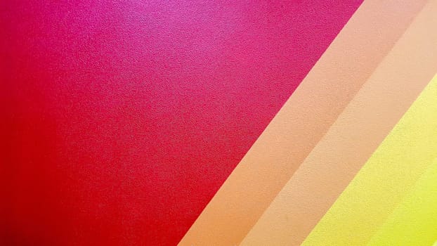 The wall is painted in red, pink, orange, yellow color with diagonal lines. Colorful background for your text and message with copy space