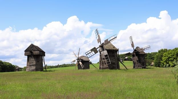 Ukraine, Kiev - June 11, 2020. Old Ukrainian wooden windmills of the XIX century. Summer outdoor landscape. Open-air museum of folk architecture and life, Pirogovo, Ukraine. Tourism and travel
