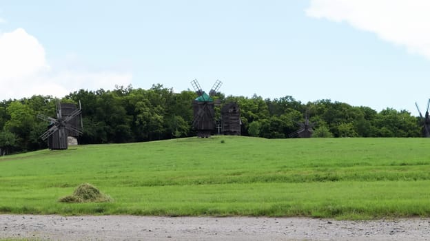 Ukraine, Kiev - June 11, 2020. Old Ukrainian wooden windmills of the XIX century. Summer outdoor landscape. Open-air museum of folk architecture and life, Pirogovo, Ukraine. Tourism and travel