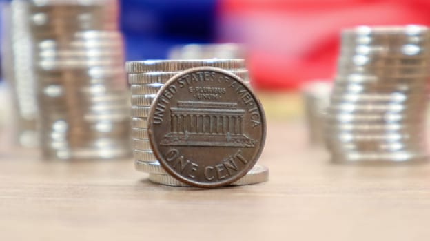 A 1 cent American dollar coin lies on the American flag. The currency is one cent over the flag of the United States.
