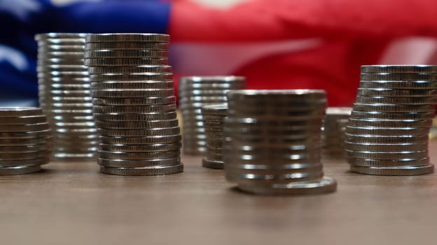 American coins with the flag of the United States of America. Investment concept, business finance and money saving. US coins stacked against the background of the American flag. Selective focus