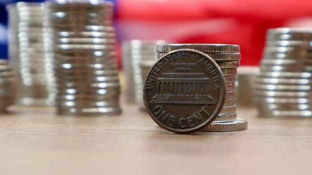 A 1 cent American dollar coin lies on the American flag. The currency is one cent over the flag of the United States.