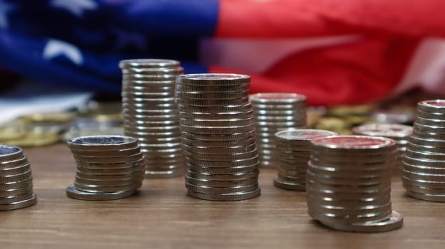 American coins with the flag of the United States of America. Investment concept, business finance and money saving. US coins stacked against the background of the American flag. Selective focus