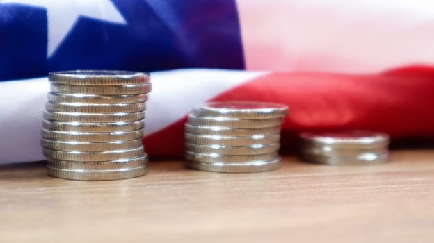 American coins with the flag of the United States of America. Investment concept, business finance and money saving. US coins stacked against the background of the American flag. Selective focus