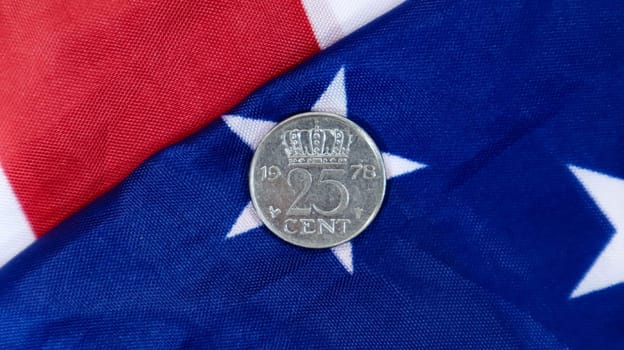 A 1 cent American dollar coin lies on the American flag. The currency is one cent over the flag of the United States