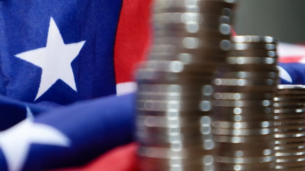 American coins with the flag of the United States of America. Investment concept, business finance and money saving. US coins stacked against the background of the American flag. Selective focus