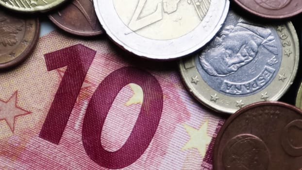 Euro banknotes and coins as background. Shot looking at the Euro currency. Coins are stacked on top of each other in different positions. Money concept