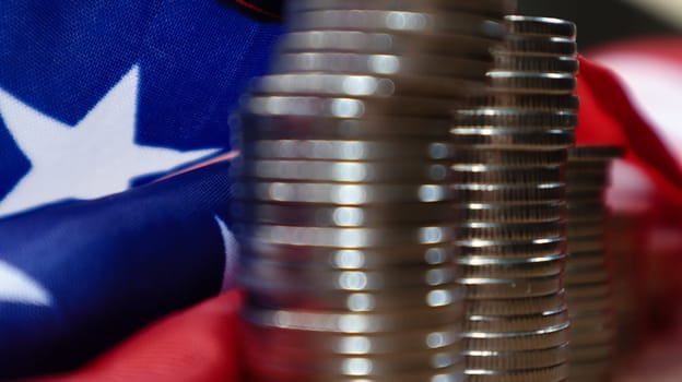 American coins with the flag of the United States of America. Investment concept, business finance and money saving. US coins stacked against the background of the American flag. Selective focus