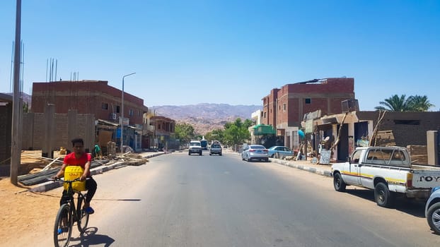 Egypt, Dahab - June 20, 2019: an Arab riding a bicycle along one of the streets of Dahab. Desert Street. Egyptian residential buildings. The city of Dahab