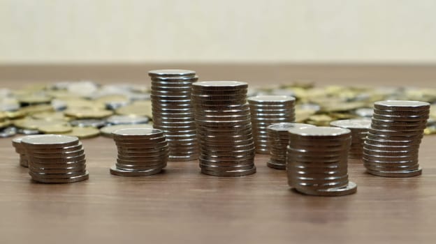 Coins are stacked on a wooden work table. Stock photo of many cents