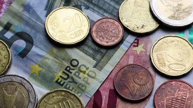 Euro banknotes and coins as background. Shot looking at the Euro currency. Coins are stacked on top of each other in different positions. Money concept
