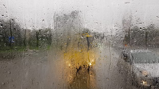 Rain on the rear window of a car in autumn. Inside view of the road with moving cars in the city through the window from the car with rain drops. driving a car in the field of view of the rear window