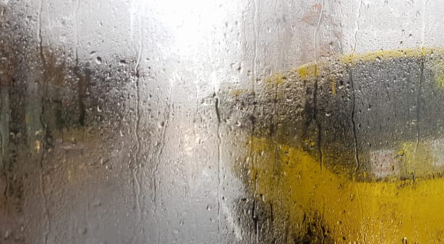 Rain on the rear window of a car in autumn. Inside view of the road with moving cars in the city through the window from the car with rain drops. driving a car in the field of view of the rear window