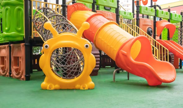 A courtyard of high-rise buildings with a new modern colorful and large playground on a rainy summer day without people. Empty outdoor playground. A place for children's games and sports